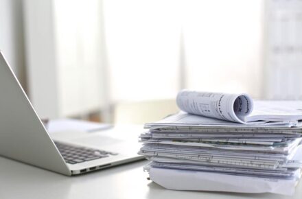 A pile of documents and a laptop.