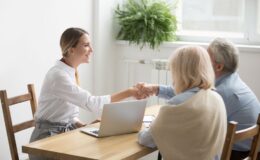 Senior couple shaking hands with woman at table