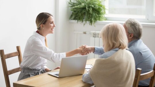 Senior couple shaking hands with woman at table