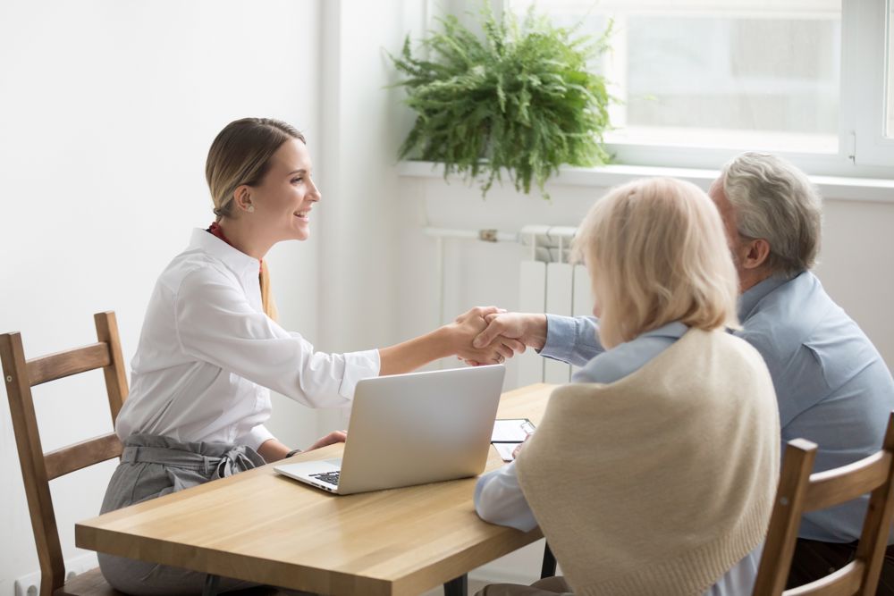 Senior couple shaking hands with woman at table